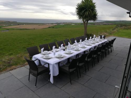 a long table with chairs and white dishes on it at Ocean View,Kinsale, Hosted by Exquisite holiday homes, sleeps 22 in Kinsale