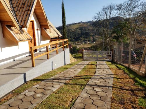 a stone walkway next to a house with a fence at Chale Vale Encantado in São Bento do Sapucaí