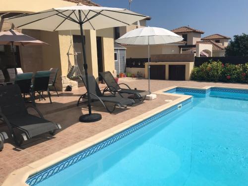 ein Swimmingpool mit Stühlen und Sonnenschirmen neben in der Unterkunft Villa Kallista in Pissouri