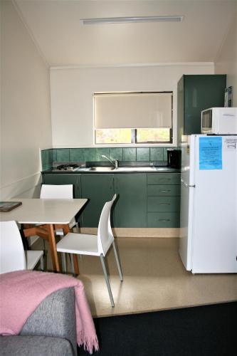 a kitchen with green cabinets and a table and a white refrigerator at Whatuwhiwhi TOP 10 Holiday Park in Tokerau Beach