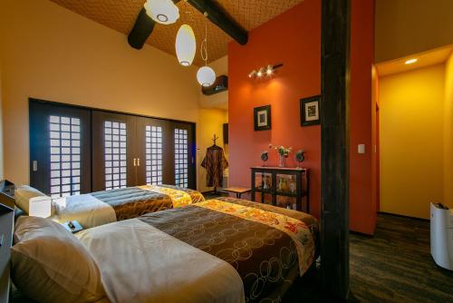 two beds in a room with orange walls at Yufuin Lamp no Yado in Yufuin