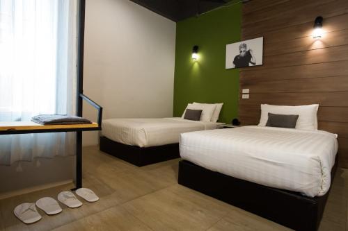 a bedroom with two beds and a green wall at The Rodman Hotel in Chiang Mai