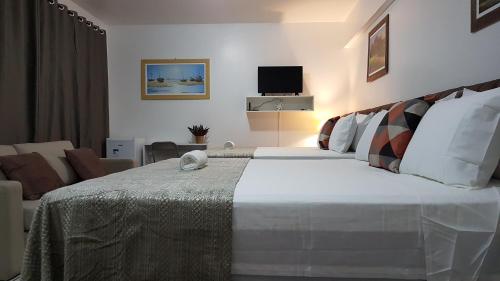 um quarto com uma cama grande e uma sala de estar em B & A Suites Inn Hotel - Quarto Luxo Palladium em Anápolis