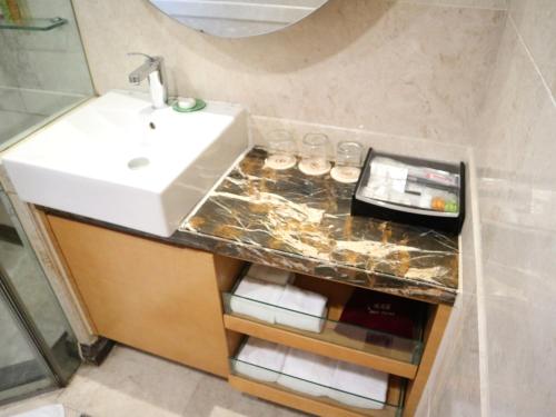 廣州的住宿－丹顿行政酒店公寓(珠江新城店)，浴室设有水槽和带玻璃杯的台面