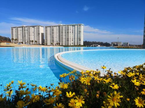 uma grande piscina com água azul e flores amarelas em Departamento en Laguna Bahia em Algarrobo