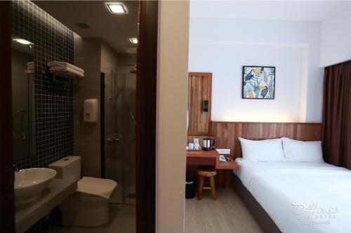 a hotel room with a bed and a sink and a bathroom at De House Hotel in Sibu