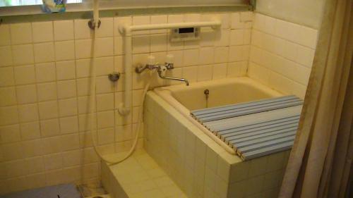 a bathroom with a bath tub with a shower at Minshuku Chatamago in Nagasaki