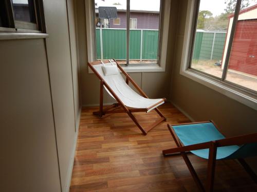 a chair in a room with two windows at Manera Heights Apartments in Dubbo