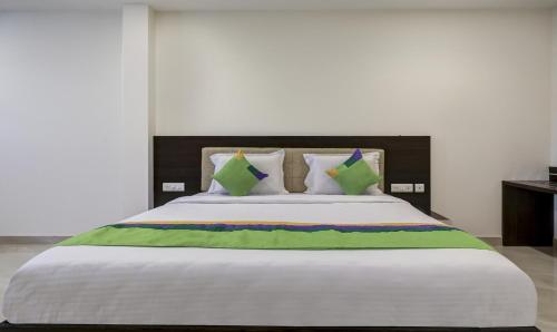 a large bed with green and white sheets and pillows at Treebo The Horizon Kankanady in Mangalore