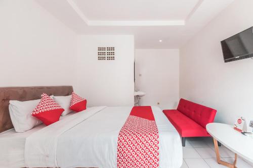 a white bed with red pillows and a red chair at OYO 947 Angel Home Stay Syariah Near Atrium Pondok Gede, Museum Monumen Pancasila, Taman Mini in Jakarta