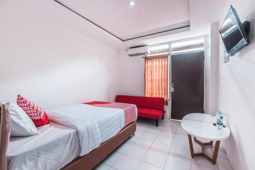 a small bedroom with a bed and a red chair at OYO 947 Angel Home Stay Syariah Near Atrium Pondok Gede, Museum Monumen Pancasila, Taman Mini in Jakarta