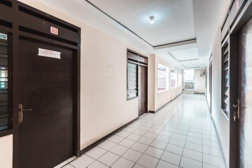 a corridor of an office with a black door at OYO 947 Angel Home Stay Syariah Near Atrium Pondok Gede, Museum Monumen Pancasila, Taman Mini in Jakarta