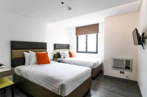 a hotel room with two beds and a television at Privato Makati in Manila
