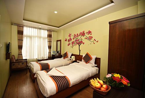 a hotel room with two beds and a tree on the wall at Hotel Osho Home in Kathmandu