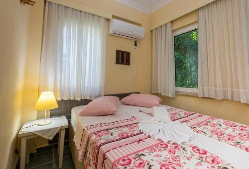 sypialnia z 2 łóżkami z różowymi poduszkami i oknem w obiekcie Villa Yasemin Aparts w mieście Göcek