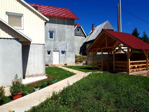 a barn with a red roof next to a building at Rondović Apartmani - Durmitor in Žabljak