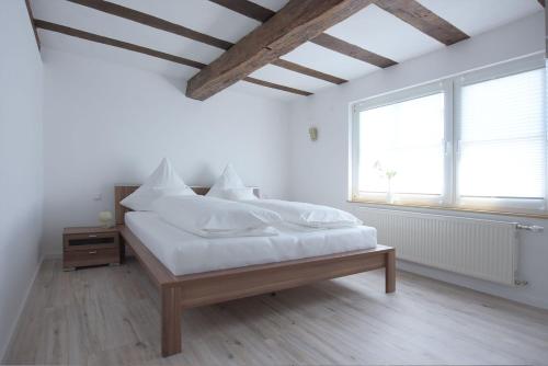 a white bedroom with a large bed with white sheets at Laubach Ferienwohnung - Fam.Lorenz in Laubach