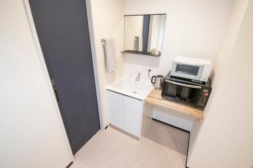 a small kitchen with a microwave and a toaster oven at UCHI Living stay NAKAJIMA park in Sapporo
