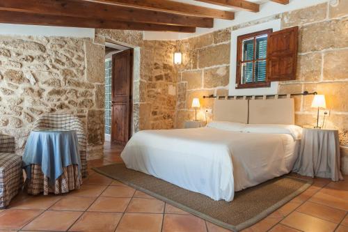 1 dormitorio con cama y pared de piedra en Hotel Can Simo, en Alcudia