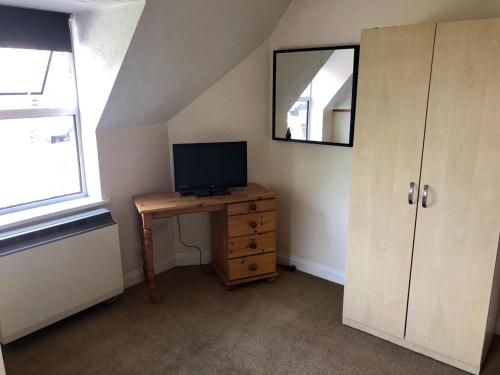 a room with a desk with a television and a mirror at Reading Budget Apartments in Reading