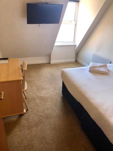 a bedroom with a bed and a desk and a window at Reading Budget Apartments in Reading