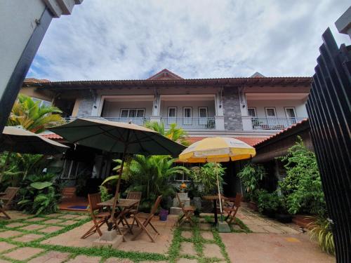 two tables and umbrellas in front of a building at Nika's House in Siem Reap