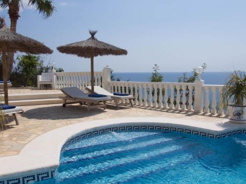 a swimming pool with two chairs and an umbrella at Frontline villa, five star deluxe in El Campello