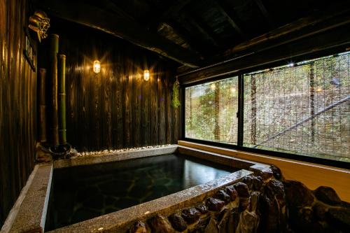 a hot tub in a room with a window at Yufuin Lamp no Yado in Yufuin