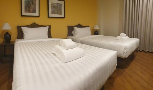 two beds in a hotel room with white sheets at Vinary Hotel Sukhumvit in Bangkok