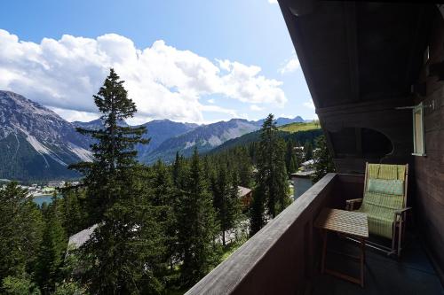 a balcony with two chairs and a view of the mountains at Hotel Arlenwald in Arosa
