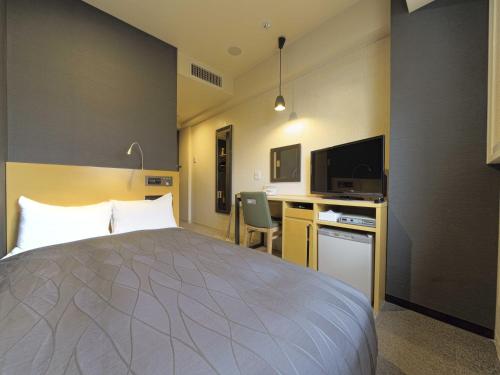 a hotel room with a bed and a desk and a tv at Meitetsu Inn Chita Handa Ekimae in Handa