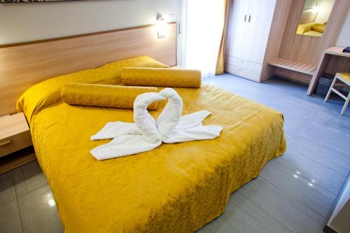 a hotel room with a yellow bed with towels on it at Motel Karibe in Fratta Polesine