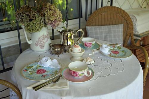 a table with plates and cups and a vase with flowers at Im Röseligarten in Wolfhausen