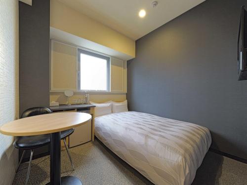 a small room with a bed and a desk and a table at Meitetsu Inn Chita Handa Ekimae in Handa