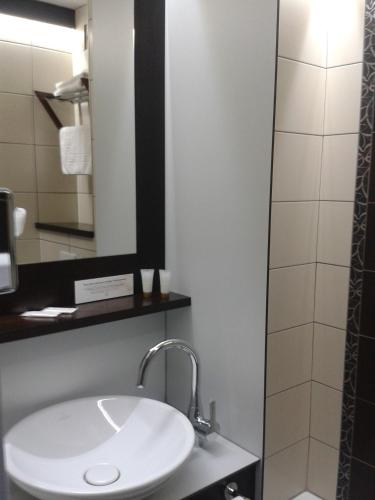 a bathroom with a white sink and a shower at Cottage Logis Hôtel - Restaurant in Dudelange