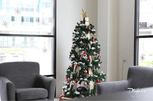 a christmas tree in a living room with two chairs at De House Hotel in Sibu