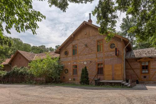 a large wooden house with a tree in front of it at Pavilon Panzió Étterem és Pizzéria in Gyomaendrőd