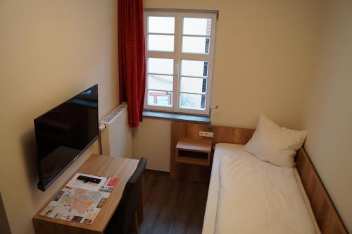 een kleine kamer met een bed en een televisie bij Braumeister Döbler - Ferienwohnungen in Bad Windsheim