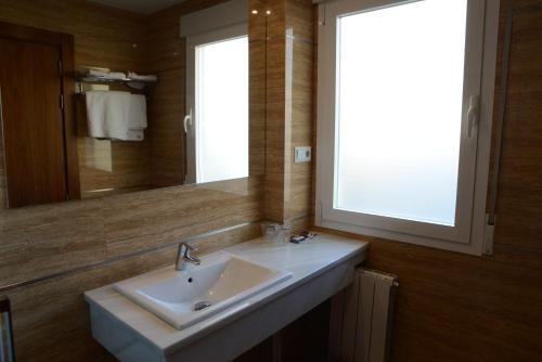 a bathroom with a sink and a window and a mirror at Hotel Escudero in Ciudad Real