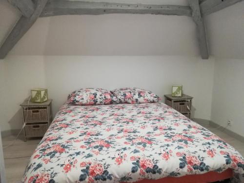 - une chambre dotée d'un lit avec un couvre-lit floral dans l'établissement Chez Flo, à Ry