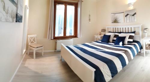 a bedroom with a bed with blue and white stripes at Gîte Les Volets Bleus in Monflanquin