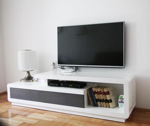 a flat screen tv sitting on a white entertainment center at River View Nis - 65 square meters Designer Apartment in heart of city Park for free in Niš