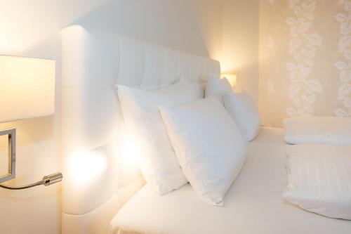 a white bed with white pillows in a room at Hotel & Spa Der Steirerhof in Bad Waltersdorf