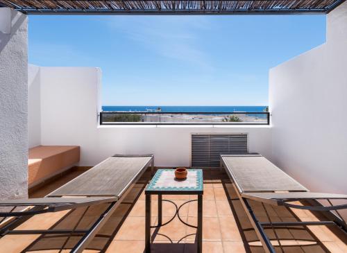 a room with two benches and a table and a window at Hotel Calachica Las Negras in Las Negras