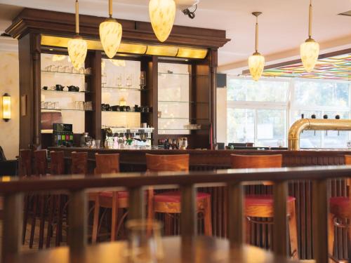 a bar in a restaurant with wooden chairs and lights at Hotel Löwenstein in Gerolstein
