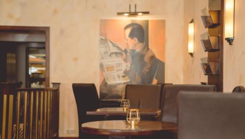 a restaurant with tables and chairs and a painting on the wall at Hotel Löwenstein in Gerolstein