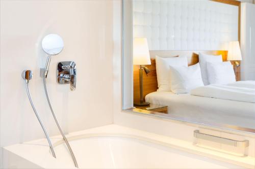 a bathroom with a mirror next to a bed at Hotel & Spa Der Steirerhof in Bad Waltersdorf