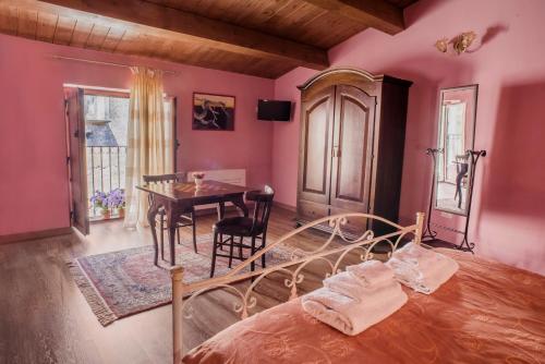 チヴィタにあるB&B Dhafnaのピンクの壁のベッドルーム(テーブル、ベッド1台付)
