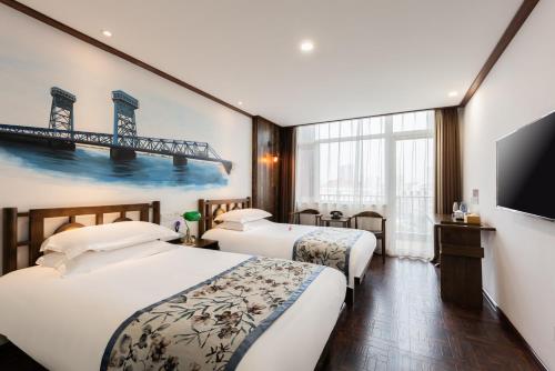 a hotel room with two beds and a television at Nostalgia Hotel Tianjin Binhai Tanggu 时光漫步酒店天津滨海塘沽站店 Free fresh ground coffee,Free laundry service in Tianjin