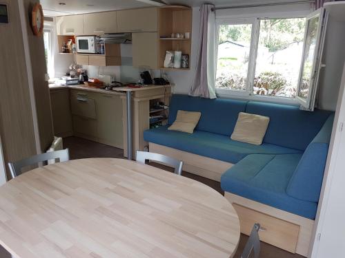 un salon avec un canapé bleu et une table dans l'établissement Mobil-home 75 au Camping Le Rioumajou, à Bourisp